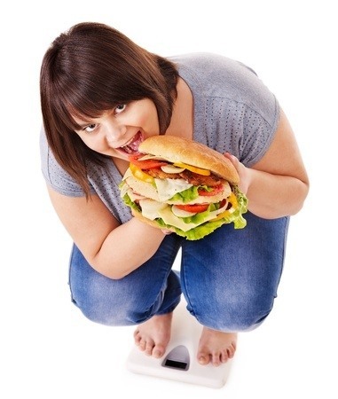 Een vrouw met overgewicht eet een hamburger